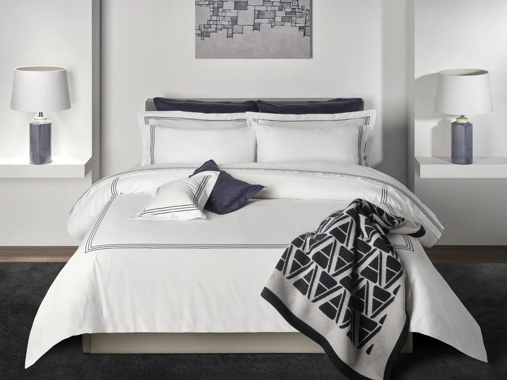 Neatly made bed with alvorada duvet cover and pillowcases and decorative pillows in a modern bedroom setting.