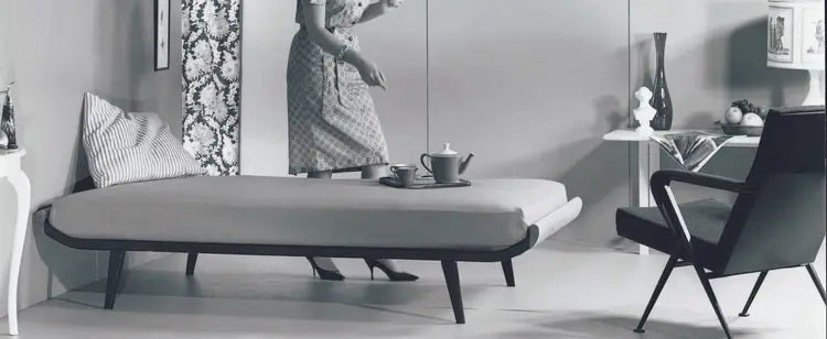 Modern bedroom with a gray sofa bed, black chair, and decorative items.