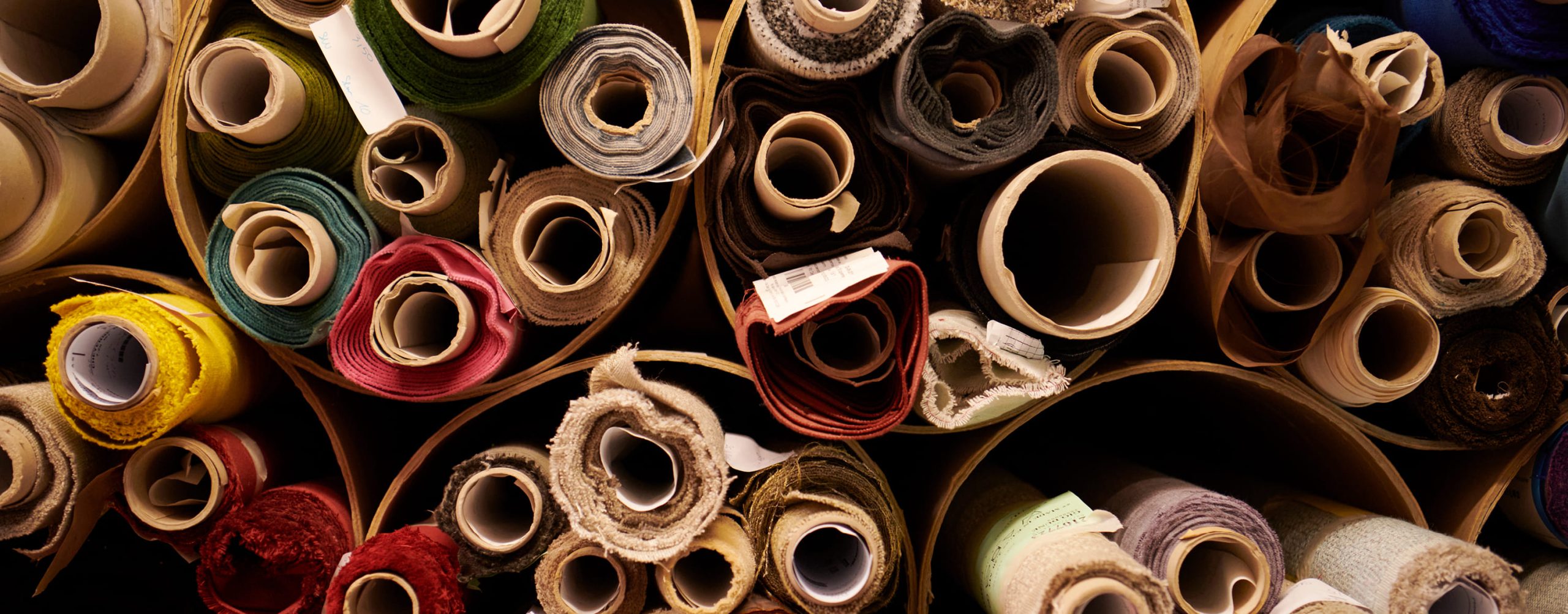 Collection of rolled-up Treca fabrics in various colors and textures.