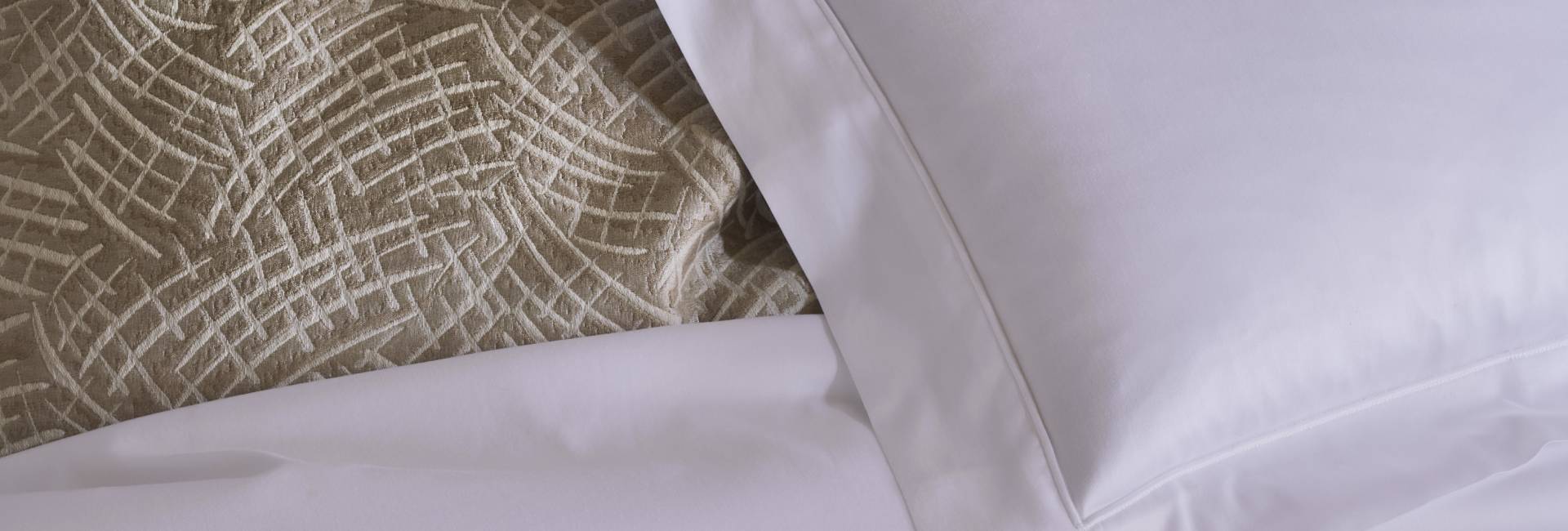 Close-up of textured fabric with a geometric pattern and white pillow