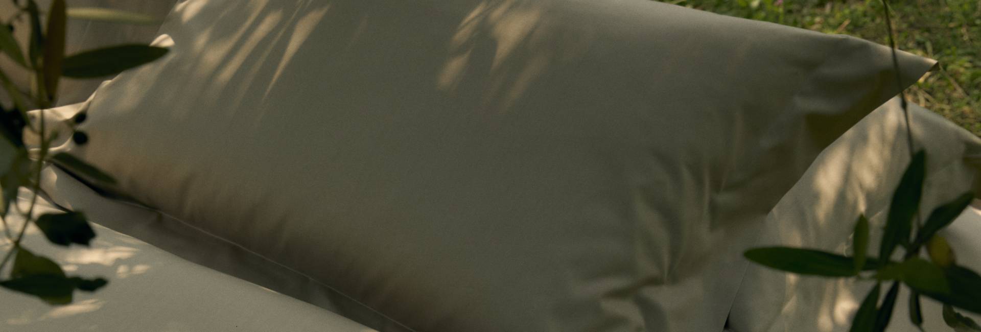 White pillow on a bed with greenery around