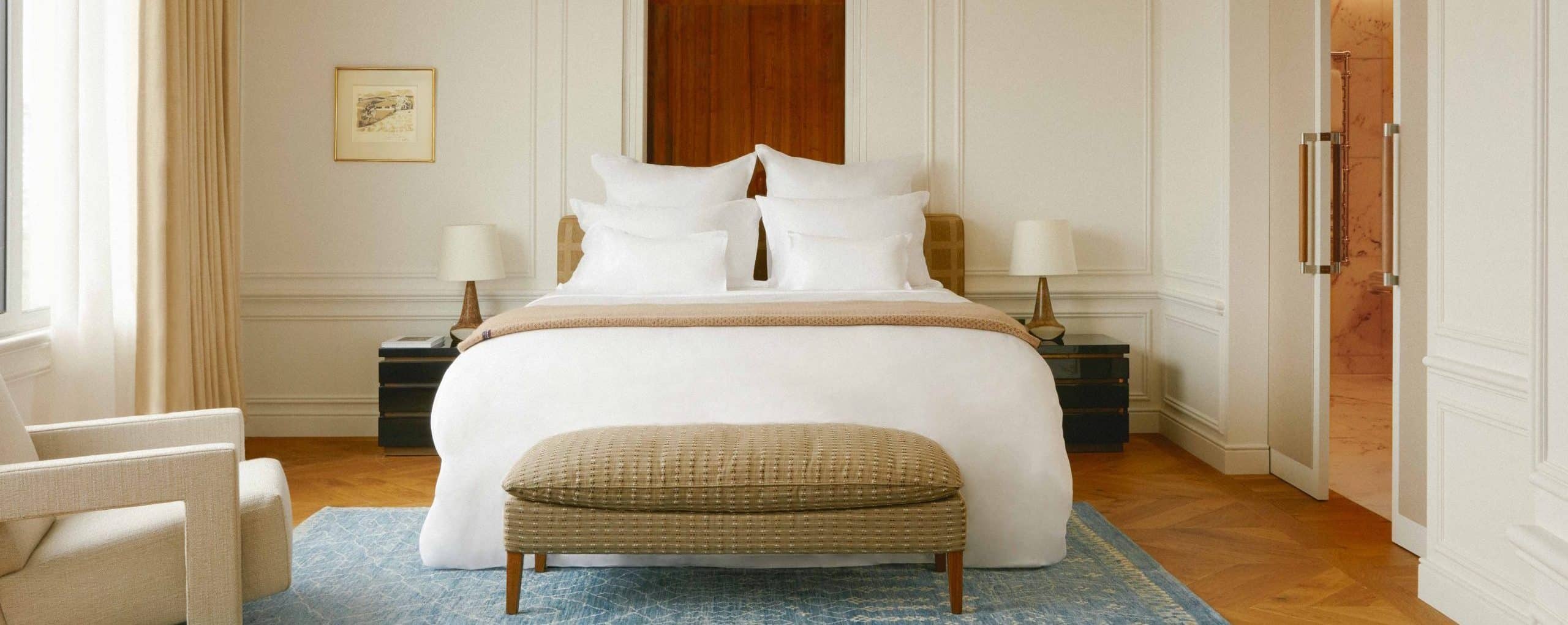 Neatly made Treca bed in a bedroom with a bench and decor